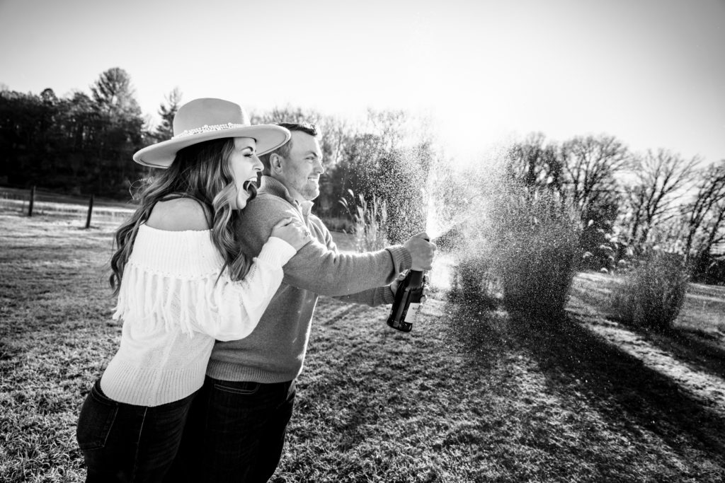 Bride and groom popping champagne during engagement session by Nathan Whitworth Greenville SC Wedding Photography